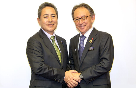玉城デニー沖縄県知事と固い握手を交わすとう山勝利